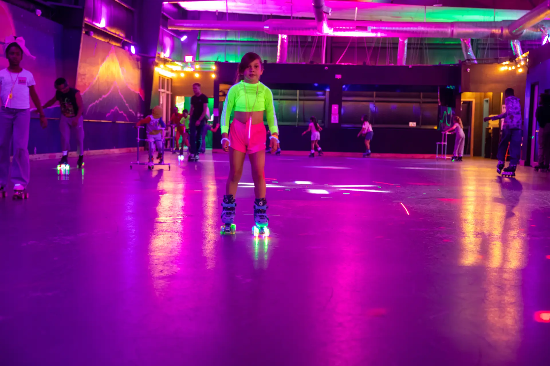 Young skater in glowing neon outfit on the rink