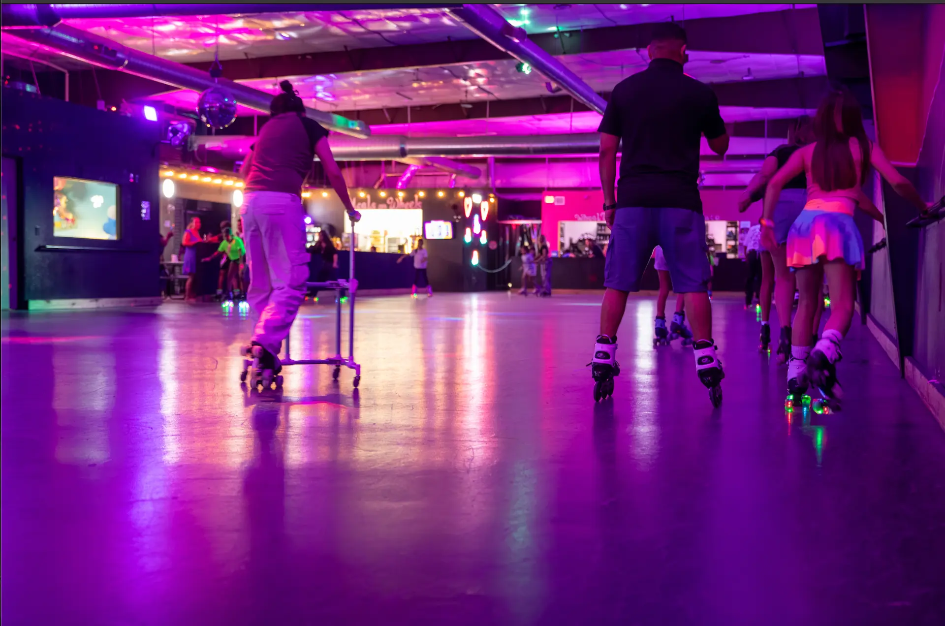 Skaters rolling across the neon-lit Spin City rink floor
